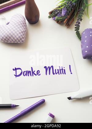 Deutsche Dankesmutter als Bürstenschriftzug auf einer Muttertagsgrußkarte auf einem weißen Tisch mit Dekoration, Happy Mothers Day Stockfoto