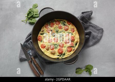 Frittata aus Eiern, Pilzen, Kirschtomaten und Spinat in einer Pfanne serviert. Italienische Küche. Stockfoto