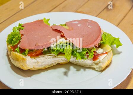 Bologna-Sandwich mit Salat, Brot, Mayonnaise und Ketchup. Natürliche und alternative Lebensmittel. Das Sandwich ist einer der bekanntesten und vielseitigsten Snacks Stockfoto