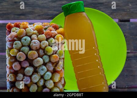 Flasche Acerola Saft in einem Turm von gefrorenen Acerola Früchte verankert. Detox trinken und reich an Vitamin c. Exotische Früchte. Natürliche Energie. Natürliche und Stockfoto