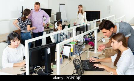 Menschen, die in modernen Büros mit Computern und Laptops arbeiten Stockfoto