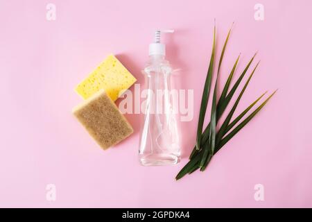 Flaches Lay mit grünem Palmblatt, Seifentropfer, Spülmittel, Spülmittel, Waschlappen auf pastellrosa und gelbem Hintergrund. Hochwertige Fotos Stockfoto