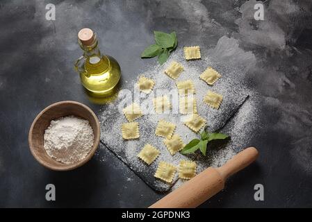 Italienische rohe Ravioli mit Pilzen, Basilikum, Mehl, Weizen, Olivenöl auf dunklem Hintergrund.Shavuot jüdischen Feiertagskost-Konzept Stockfoto