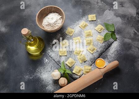 Italienische rohe Ravioli mit Pilzen, Basilikum, Mehl, Weizen, Olivenöl auf dunklem Hintergrund.Shavuot jüdischen Feiertagskost-Konzept Stockfoto