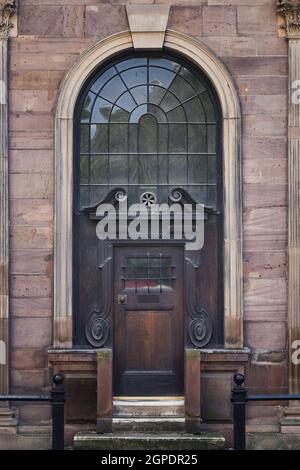 Alte alte massive Holztür an der Seite der historischen Steinkirche. Solide Außentür-Architektur in Torbögen über Fenstern geschlossen hohe Sicherheit. Stockfoto