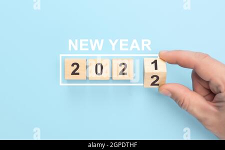 Neues Jahr 2021 Änderung zum 2022 Konzept. Hand über Holzwürfelblock drehen. Drehen von Holzwürfeln Block zu ändern 2021 bis 2022 Jahr. Frohe Weihnachten und Stockfoto