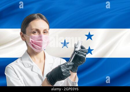 Die Ärztin bereitet die Impfung vor dem Hintergrund der Flagge von Honduras vor. Impfkonzept Honduras. Stockfoto