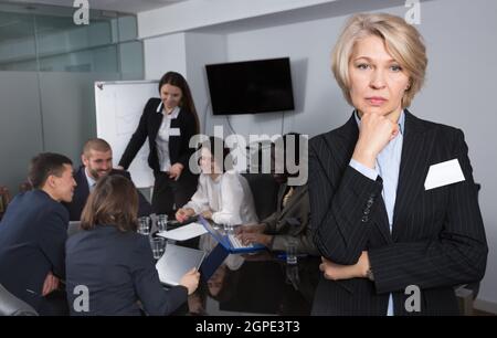 Verärgerte reife Geschäftsfrau, die im Tagungsraum stand Stockfoto