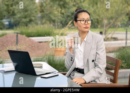 Junge Geschäftsfrau mit einer Tasse Tee oder Kaffee, die eine Pause im Café im Freien genießt Stockfoto