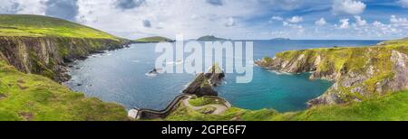 Wunderschöne Panoramaaufnahme des beeindruckenden Dunquin Pier und Hafens mit hohen Klippen, türkisfarbenem Wasser und Inseln, Dingle, Wild Atlantic Way, Kerry, Irland Stockfoto