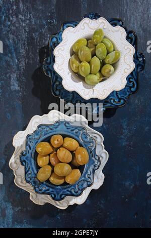 Zwei Olivensorten in Keramikplatten auf blauem Hintergrund. Gesunde natürliche Nahrung. Ein starkes Antioxidans und ein gesundes Produkt. Draufsicht. Vertikal Pho Stockfoto