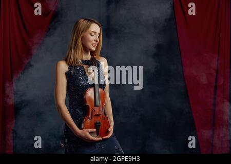 Geigerin im Retro-Stil. Frau mit Streichmusikinstrument, Musikkunst, Musikerspiel auf Viola, dunkler Hintergrund Stockfoto