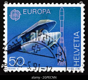 SCHWEIZ - UM 1991: Ein Stempel, der in der Schweiz gedruckt wurde, zeigt Ariane Payload Fairing, Nasenkegel, der zum Schutz eines Raumschiffs verwendet wurde, um 1991 Stockfoto