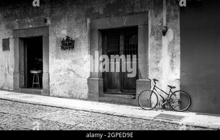 Schwarz-Weiß-Bild von einmundem Fahrrad vor dem Café in Cartagena, Kolumbien, Südamerika. Keine Personen. Stockfoto