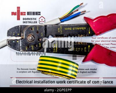 NICEIC-Konformitätszertifikat – National Inspection Council for Electrical Installation Contracting – mit Abisolierzangen, Kabel und Klebeband auf der Oberseite. Stockfoto