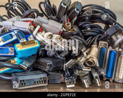 Nahaufnahme eines Stapels alter Computer-, Audio-, Video- und Fernsehkabel mit einer Auswahl an Steckern/Buchsen/Anschlüssen. Stockfoto