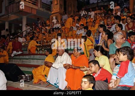 Zuschauer, Gläubige, Anhänger und Priester in orangefarbenen Gewändern in der heiligen Stadt Rishikesh in Uttarakhand, Indien während der abendlichen Lichtzeremonie cal Stockfoto