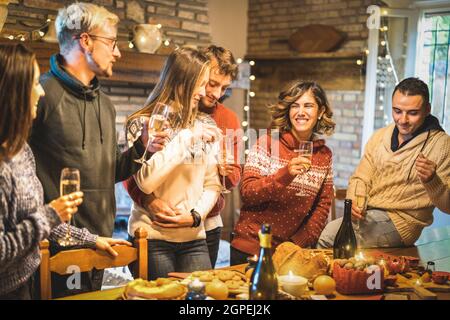 Happy Friends Gruppe feiert Weihnachtsfeier mit Weißwein und süßem Essen beim Abendessen Abendessen - Winterurlaub Konzept mit jungen Menschen Stockfoto