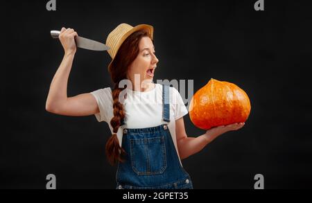 Farmer auf schwarzem Hintergrund greift einen reifen Kürbis mit einem scharfen Messer an. Stockfoto