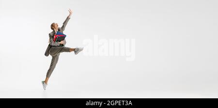 Ganzkörperportrait einer glücklichen weiblichen Mitarbeiterin in klassischem Anzug mit einem Ordner, der wie eine Ballerina auf weißem Hintergrund springt. Flyer Stockfoto