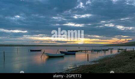 Sonnenuntergangsbild von Fischerbooten auf der Flottenlagune auf der Landseite des Chesil-Ufers in Chickerell, Dorset, England Stockfoto