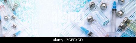 Medizinische Fläschchen, Spritzen und Maske auf grünem Hintergrund. Prävention von saisonalen Krankheiten. Impfung gegen Covid-19. Stockfoto