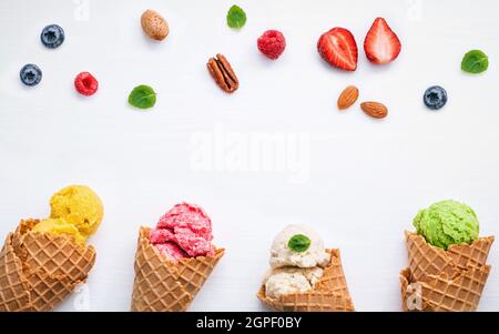 Bunte Eis mit Kegel und verschiedene Früchte Himbeere, Heidelbeere, Erdbeere und Pfefferminze Blätter setup auf weißem Hintergrund flach und s kopieren Stockfoto