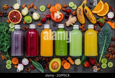 Bunte gesunde Smoothies und Säfte in Flaschen mit frischen tropischen Früchten und Superfoods auf dunklem Stein Hintergrund mit kopieren. Stockfoto