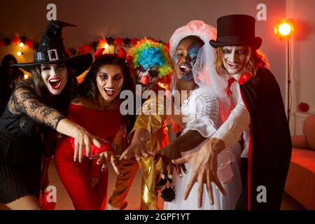 Eine Gruppe junger Freunde in gruseligen Kostümen, die zusammen Spaß auf der Halloween Party haben Stockfoto