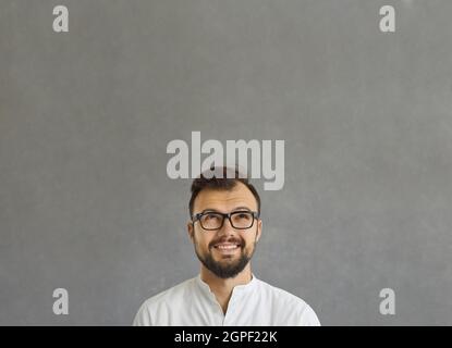 Nahaufnahme eines nachdenklichen jungen, nachdenklichen Geschäftsmannes, der auf Grau aufschaut Stockfoto