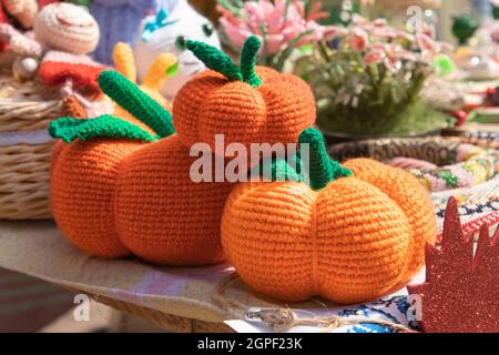 Natürliches Dekor für Halloween. Gehäkelt aus Fadenkürbis auf der Herbstmesse. Handgemachte orangefarbene Kürbisse auf einem ländlichen Fest zu Halloween. Stockfoto