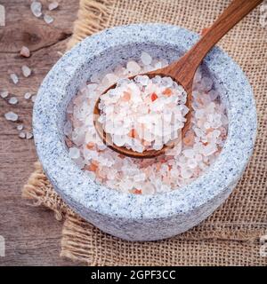 Himalaya Pink salt in Mörtel auf Hanf sack Hintergrund. Himalaya-salz häufig in Kochen und für Badewanne Produkte wie Badesalz verwendet Stockfoto