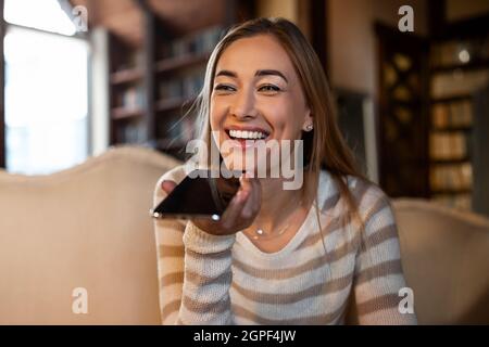 Nahaufnahme einer glücklichen Frau mit einem Sprachassistenten auf dem Handy Stockfoto