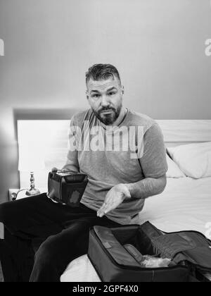 Unglücklich schockiert Mann mit chronischen Atemproblemen überrascht, indem CPAP-Maschine auf dem Bett im Schlafzimmer sitzen. Stockfoto