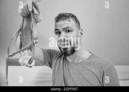 Unglücklich schockiert Mann mit chronischen Atemproblemen überrascht, indem CPAP-Maschine auf dem Bett im Schlafzimmer sitzen. Stockfoto