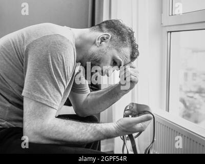 Unglücklich schockiert Mann mit chronischen Atemproblemen überrascht, indem CPAP-Maschine auf dem Bett im Schlafzimmer sitzen. Stockfoto