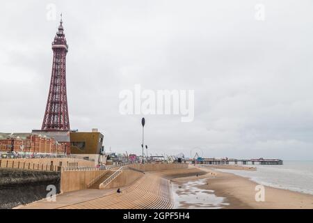 Blackpool Tower, der an einem bewölkten Morgen im September 2021 neben dem Central Pier abgebildet ist, während die Flut langsam den Strand bedeckt. Stockfoto