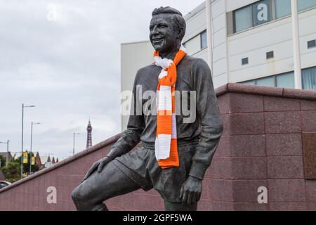 Eine Statue des ehemaligen Blackpool FC-Spielers und Managers Jimmy Armfield vor dem Bloomfield Road Stadion im September 2021 mit dem Blackpool Tower in t gesehen Stockfoto
