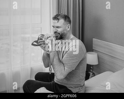 Reifer glücklicher Mann mit chronischen Atemproblemen erwägt die Verwendung CPAP-Maschine auf dem Bett im Schlafzimmer sitzen. Gesundheitswesen, CPAP, Schnarchen Konzept Stockfoto