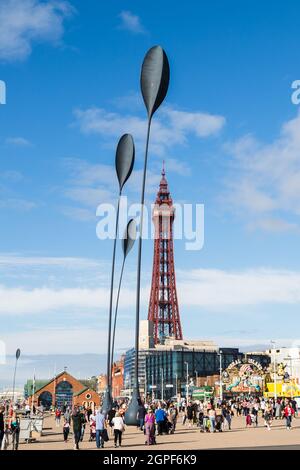 Touristen, die im September 2021 unter den vier riesigen Löffelskulpturen, dem Blackpool Tower und dem Blackpool RNLI-Gebäude am Wasser zu sehen waren. Stockfoto