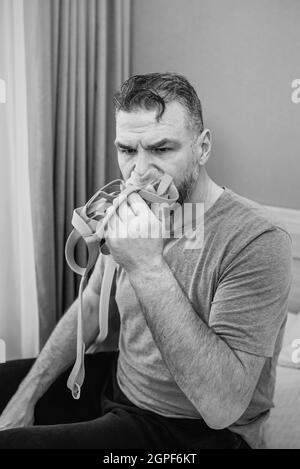 Unglücklich schockiert Mann mit chronischen Atemproblemen überrascht, indem CPAP-Maschine auf dem Bett im Schlafzimmer sitzen. Stockfoto