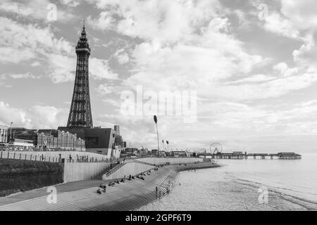 Blackpool Tower und der Central Pier in monochromer Darstellung vom North Pier aus, der die geschwungenen Stufen entlang der Uferpromenade betrachtet. Stockfoto