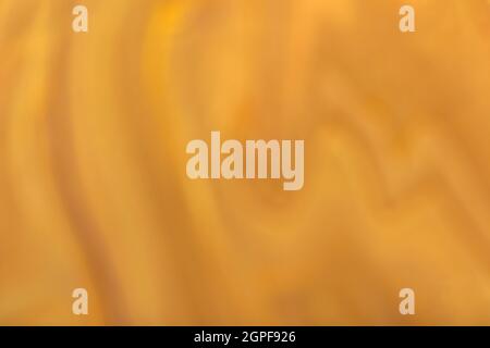 Verschwommener dunkeloranger und goldener Hintergrund mit Wellenmuster. Defokussierte, abstrakte ockerfarbene Hintergrundkulisse mit Unschärfe und Bokeh. Verschwommenes Hintergrundbild. Stockfoto