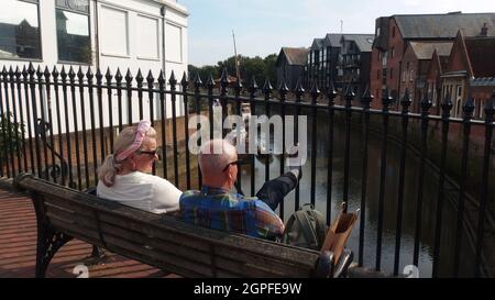 Ein Paar, das an der Brücke über den Fluss Ouse in der Cliffe High Street, Lewes, an einem sonnigen späten Septembernachmittag sitzt Stockfoto