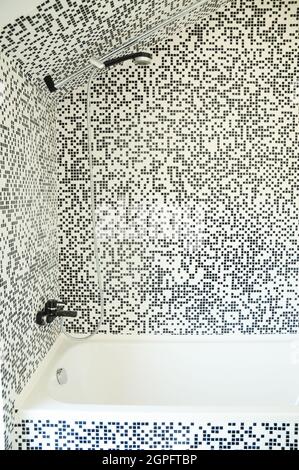 Moderne Badewanne mit Dusche, Chrom-Wasserhahn und modernen Mosaikfliesen Stockfoto