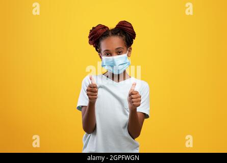 Freundliche afro-amerikanische weibliche Kind trägt schützende Gesichtsmaske Stockfoto