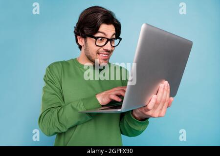 Porträt von jungen funky lustigen Geek Nerd lächelnden Geschäftsmann arbeitet in Netbook isoliert auf blauem Hintergrund Stockfoto