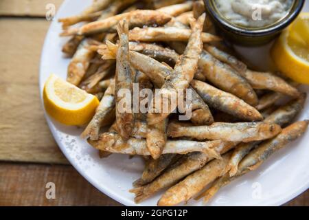 Frittierte Sprossen, Sprattus Sprattus, serviert mit Zitronenkeilchen und Tartaresauce, gefangen in Lyme Bay Dorset. Sprotten sind ein kleiner, schhohlender Fisch, der ar Stockfoto