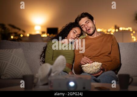 Gelangweilt Paar Schlafen Film Über Projektor Sitzen Zu Hause Stockfoto