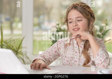 Nettes kleines Mädchen mit Laptop zu Hause Stockfoto